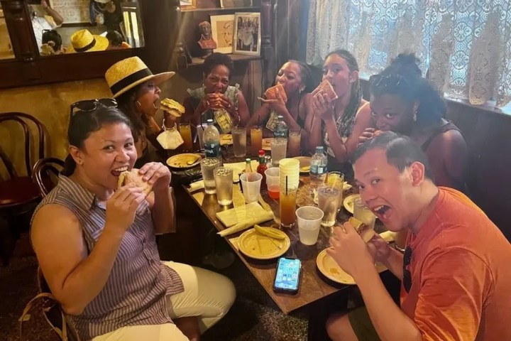Group of people enjoying sandwiches in a cozy restaurant setting.