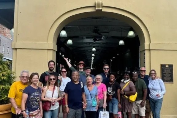 Group of people smiling in front of French Market entrance.