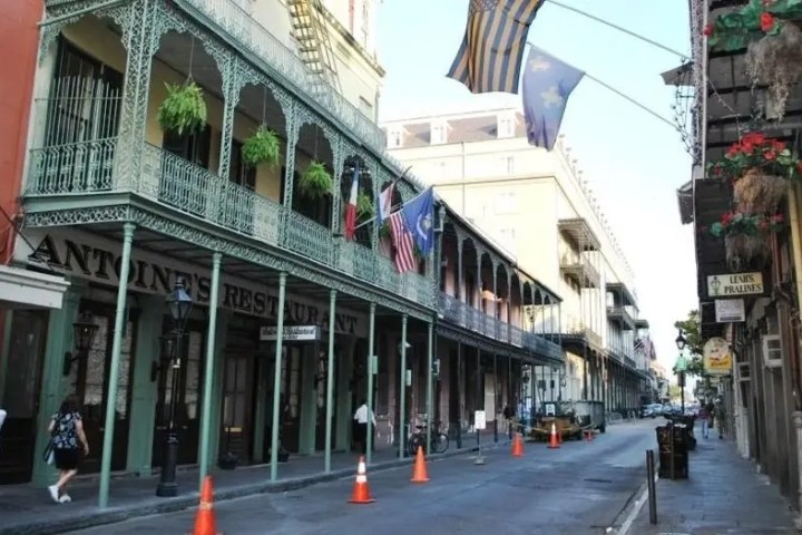 Street with historic building, iron balconies, and flags in urban setting.
