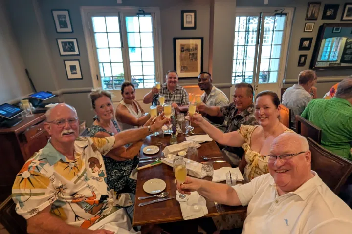 Group of people toasting with drinks at a restaurant table.