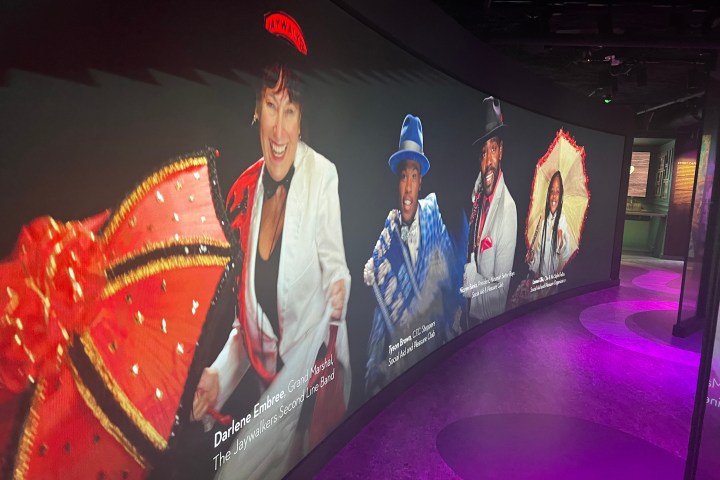Curved display with images of people in vibrant costumes and text labels on a lit purple floor.
