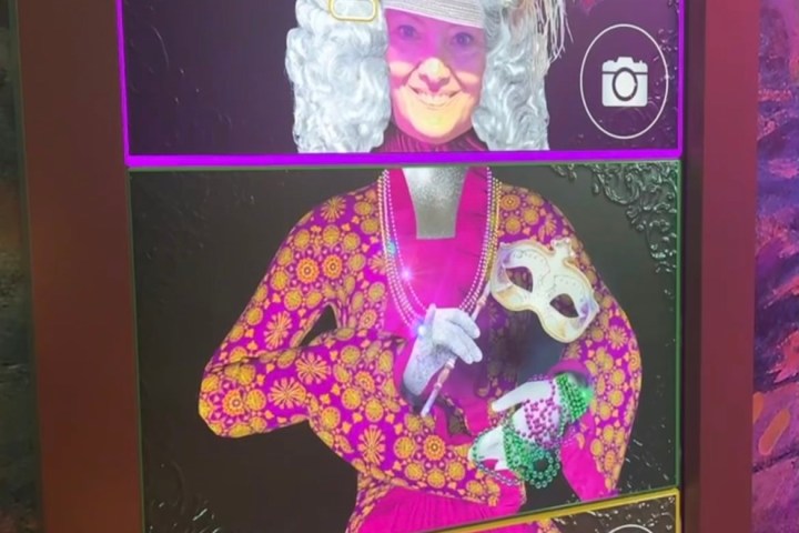 Interactive screen with a person wearing a colorful costume and wig in a photo booth.