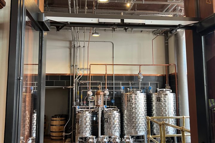 Entrance to a distillery with metal tanks and pipes visible inside.