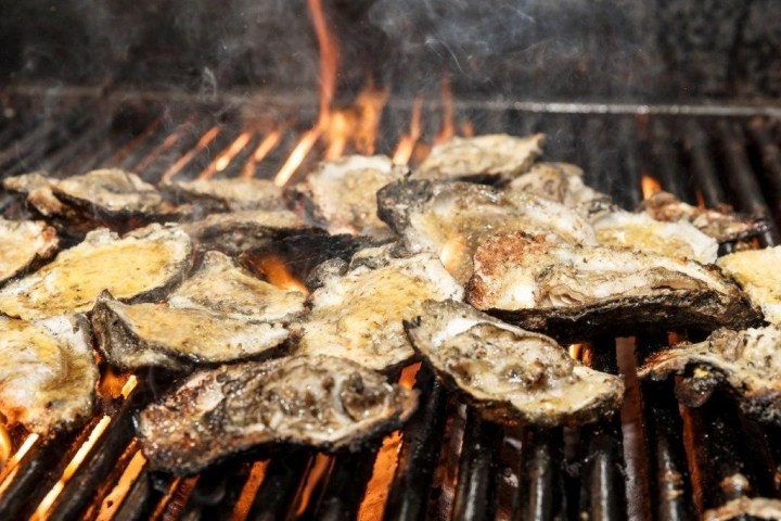 Grilled oysters on a flaming barbecue.