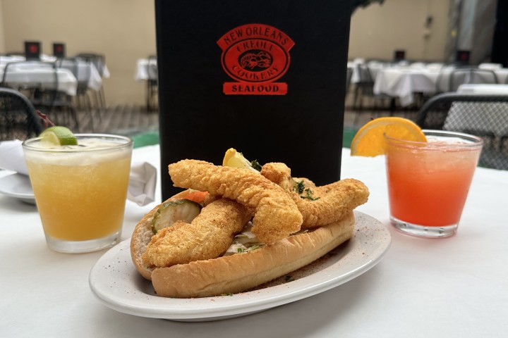Seafood sandwich with two cocktails on an outdoor table.