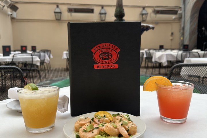 Drinks, shrimp dish, and seafood menu on outdoor table.